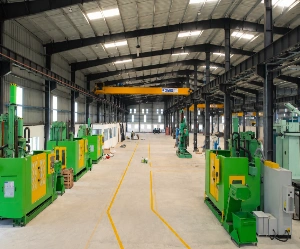 Interior view of industrial PEB manufacturing facility with heavy machinery and crane system